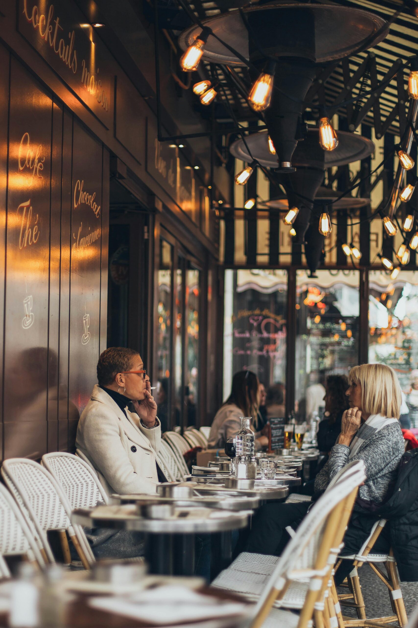Adults enjoying conversation and drinks in a stylish outdoor cafe setting.